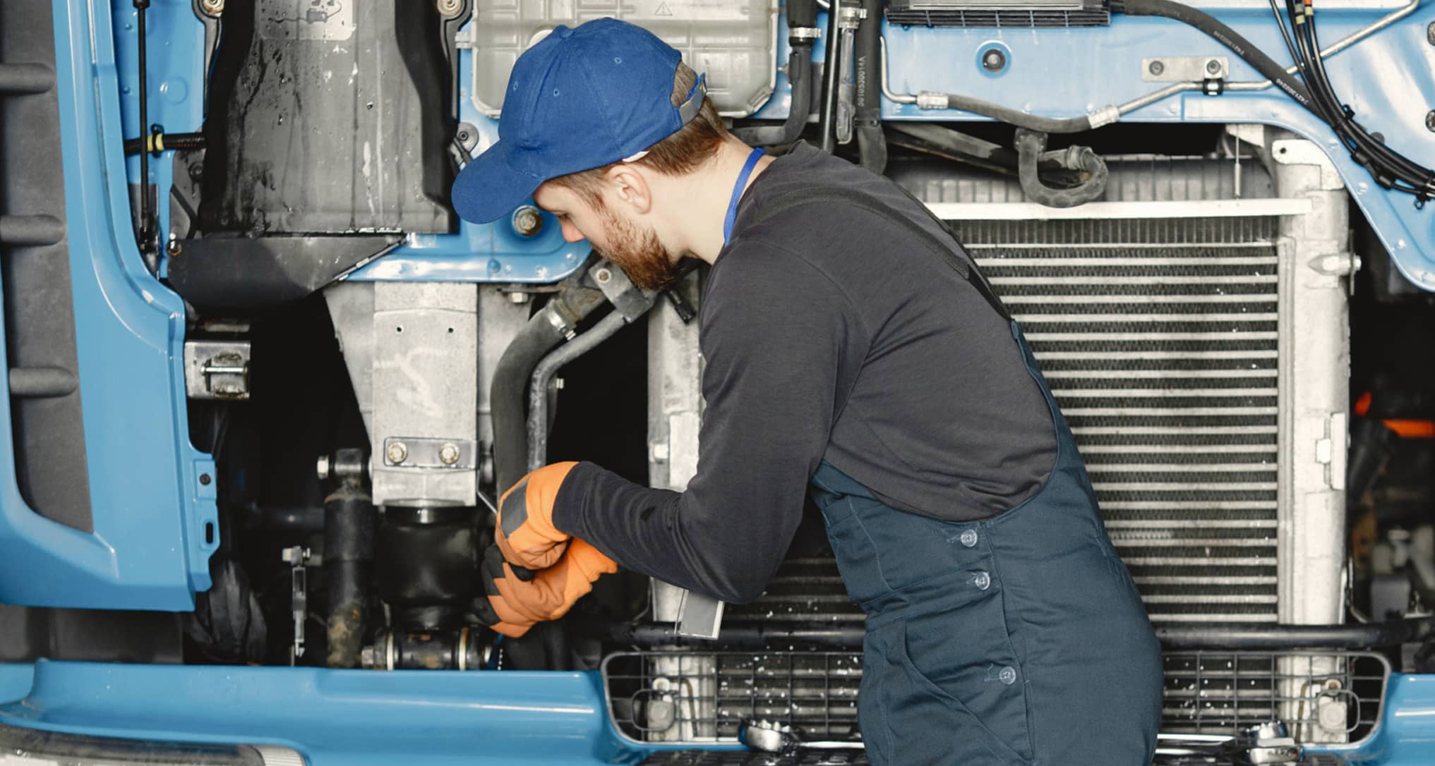 Worker checks quality of truck in garage in uniform